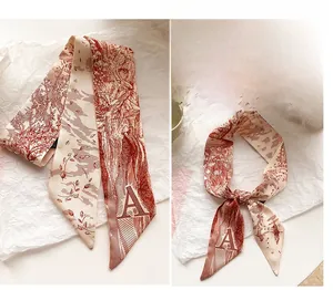 Détail d'un foulard en satin terre cuite avec imprimé floral et monogramme lettre A