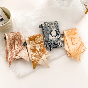 Détail de quatre foulards twilly colorés avec imprimé LOVE sur fond de papier froissé