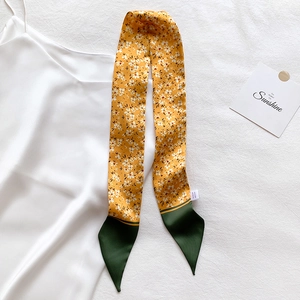 Detail of floral skinny scarf in yellow and green with brand label on silk background