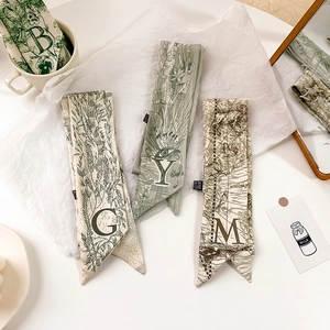 Détail de foulards étroits en soie élégants avec motifs floraux et imprimés de lettres