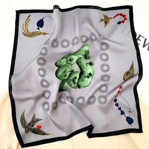 Detail eines grauvioletten Seidenschals mit goldenen Schwalben und Blumenmuster