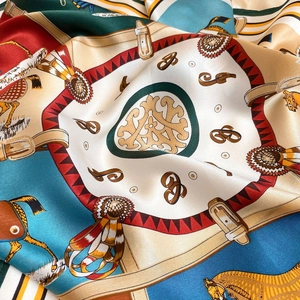 Dettaglio di un foulard in seta con motivi equestri, cavalli e briglie su tessuto blu
