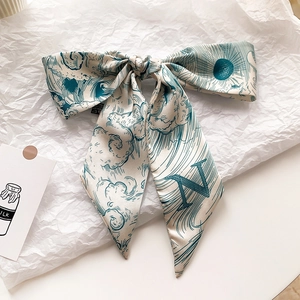 Détail d'un foulard en soie noué avec imprimé vagues japonaises et la lettre N