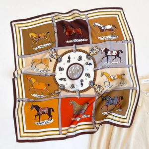 Vista macro di un foulard in seta con motivi equestri e vivaci tonalità arancioni e marroni