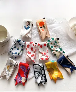 Dettaglio di vari foulard stretti in seta con stampe floreali e di frutta su bianco