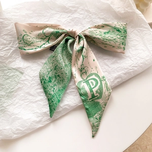 Détail d'un foulard en soie avec motifs vintage verts et une lettre P majuscule