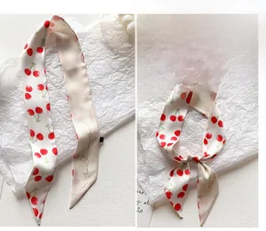 Dettaglio di un foulard sottile in seta bianca con vivaci motivi a ciliegia rossa e texture
