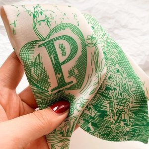 Détail macro d'un foulard en soie avec la lettre P verte et des motifs de plantes