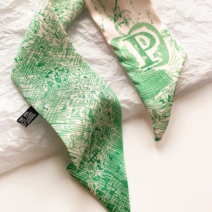 Détail d'un foulard en soie avec la lettre P verte et des motifs de mailles fines