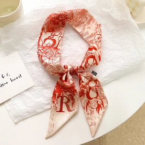 Vue détaillée d'un foulard en soie rouge et blanc avec la lettre R et des motifs floraux