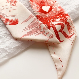 Vue macro d'un foulard en soie twilly avec lettre R vintage rouge et motifs de cœurs