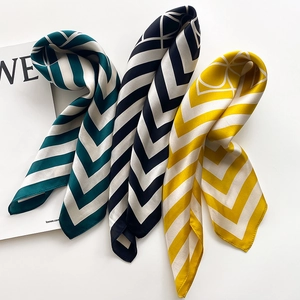 Detailed view of silk scarves with geometric V-patterns in green, black, and yellow