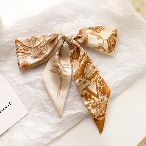 Détail d'un élégant foulard en soie beige avec motifs d'oiseaux vintage et lettre V
