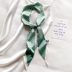 Detail of mint green striped narrow silk scarf tied on a white satin dress handle