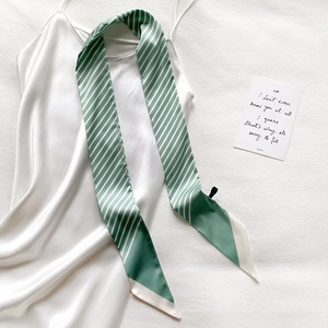 Detail showing green and white striped twilly silk scarf draped on white silk dress