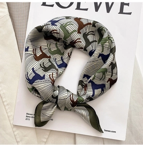 Close-up of silk square scarf showing detailed horse prints and olive green border texture