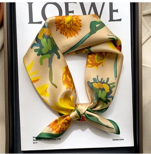 Gros plan d'un élégant foulard en soie aux motifs floraux jaunes et bords roulés