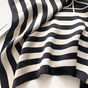 Close-up of elegant black and white striped silk scarf with premium satin texture and hem