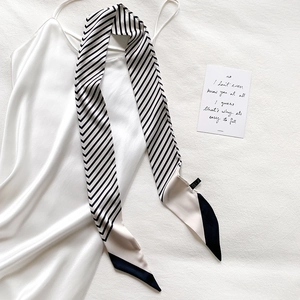 Detail of a black and white striped skinny silk scarf with elegant satin finish on fabric