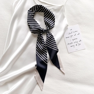 Classic black and white striped skinny silk scarf styled as a bow on a white satin top