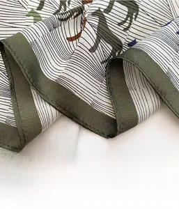 Close-up of dark green machine-rolled edges on a silk scarf with abstract animal patterns