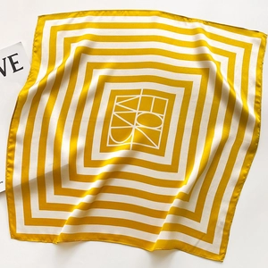 Detailed top view of striped yellow and white silk square scarf with geometric logo