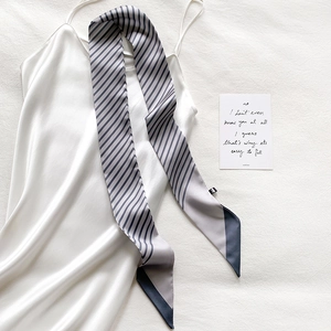 Close-up of striped narrow silk scarf on satin dress with elegant artistic background