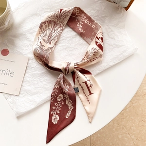 Détail de la lettre F artistique imprimée sur un foulard étroit crème et bordeaux effet soie
