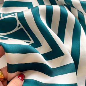 Detail of silk scarf showing deep green stripes and smooth fabric texture close-up