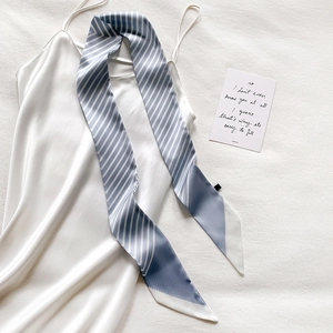 Close-up of blue and white striped silk scarf tied on a white satin slip dress