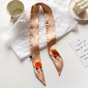 Dettaglio di un foulard twilly champagne con motivi floreali e illustrazione di ragazza