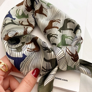 Detailed view of silk square scarf featuring elegant horse patterns and striped textures