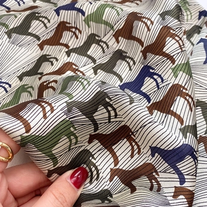 Macro detail of silk scarf showing vintage horse print and premium smooth texture