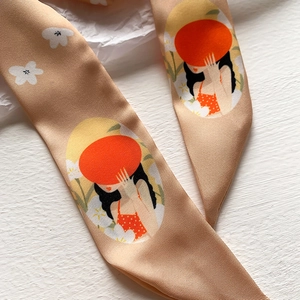 Dettaglio di foulard in seta champagne con illustrazione di una donna e motivi floreali