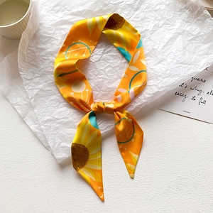 Dettaglio di sciarpa in seta gialla con stampa girasole su sfondo bianco testurizzato