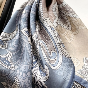 Détail d'un foulard en soie avec motifs paisley reflet satiné et ourlet roulé fin