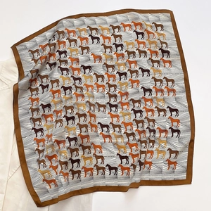 Detailed view of silk square scarf featuring elegant horse patterns and brown borders