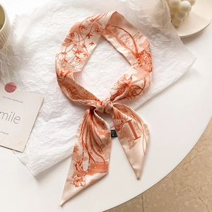 Détail d'un foulard en soie 100% avec motifs floraux orange corail sur fond blanc cassé