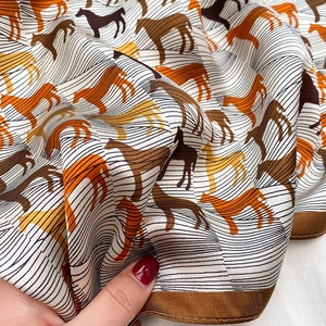 Detail of silk scarf with equestrian horse print showing smooth texture and drape
