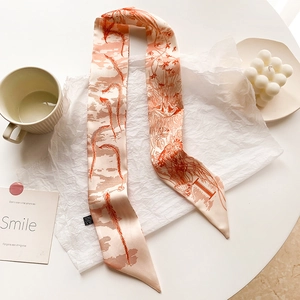 Détail de l'écharpe twilly avec imprimé botanique orange corail et texture en soie
