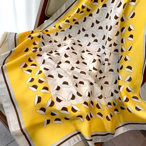 Detailed view of yellow floral silk scarf draped on a wooden chair with soft natural light