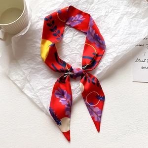 Dettaglio di un foulard Twilly rosso con stampa floreale su sfondo di carta bianca