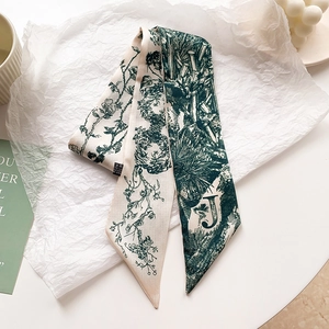 Gros plan détaillé d'un foulard en soie long avec motif floral vert et lettre J