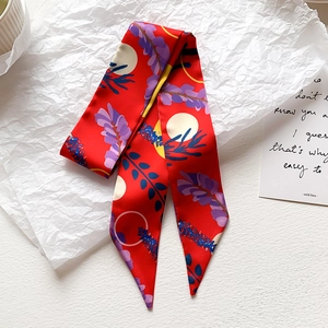 Dettaglio della sciarpa in seta rossa con fiori viola e motivi geometrici gialli
