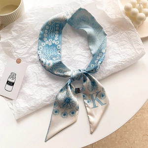 Gros plan d'un foulard en soie à fleurs bleues avec la lettre K sur fond artistique