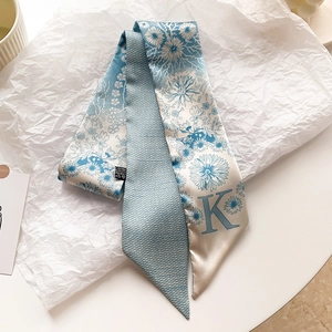 Détail d'un foulard en soie bleu et blanc à motif floral avec la lettre K