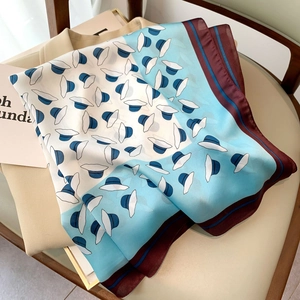 Blue hat print square silk scarf with burgundy border over beige clothing on a chair