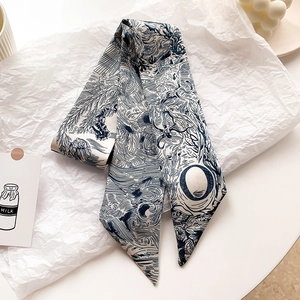 Détail d'un foulard étroit en soie avec motifs de feuilles bleues sur papier de soie