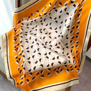 Detail of floral silk scarf showing smooth satin texture on a wooden chair