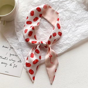Dettaglio di un foulard in seta rosa con motivi di agrumi rossi e finitura setosa fine